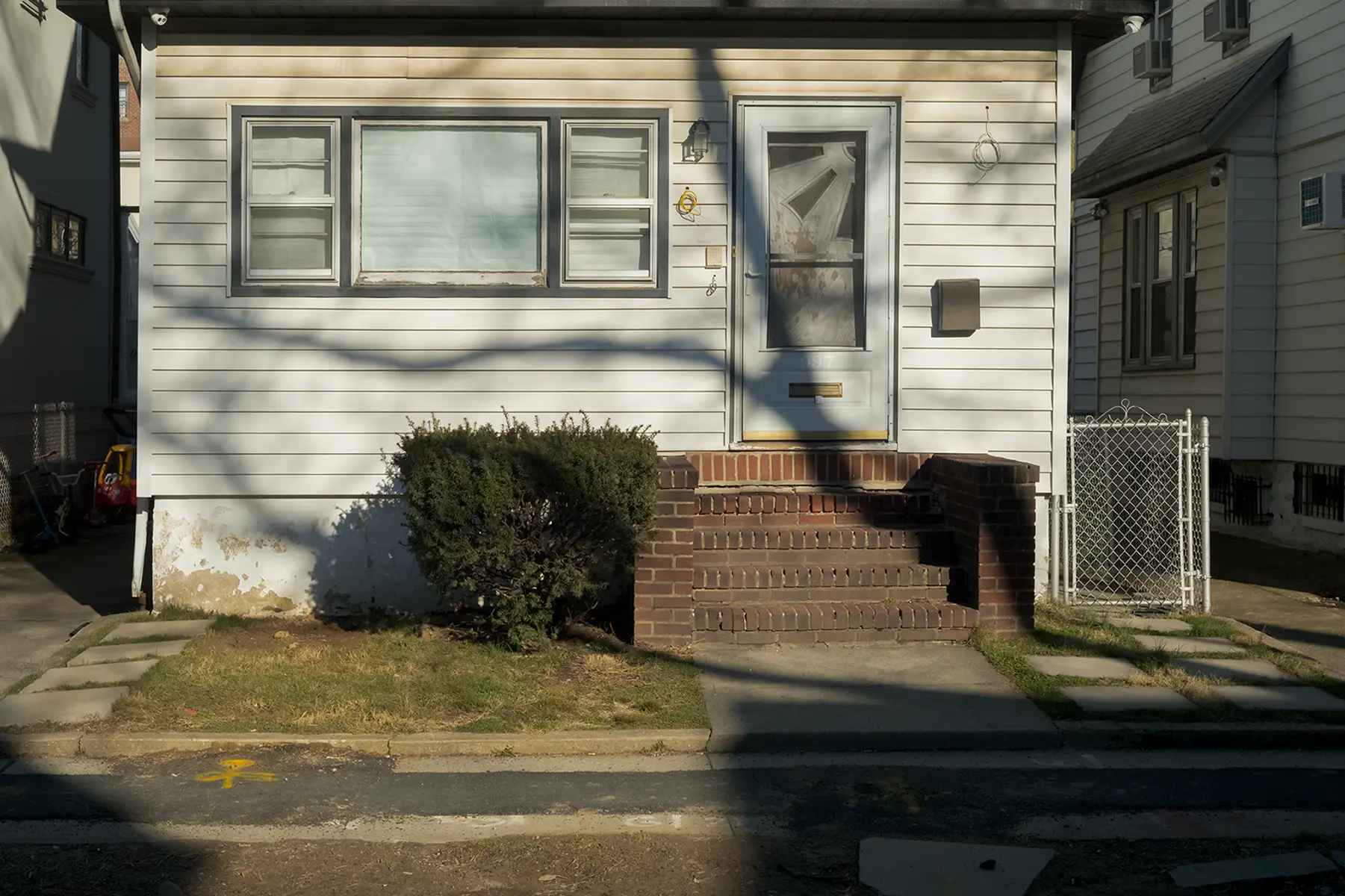 Shadows of the branches of a tree wrap around the bay windows on a home in Brookly, NY.